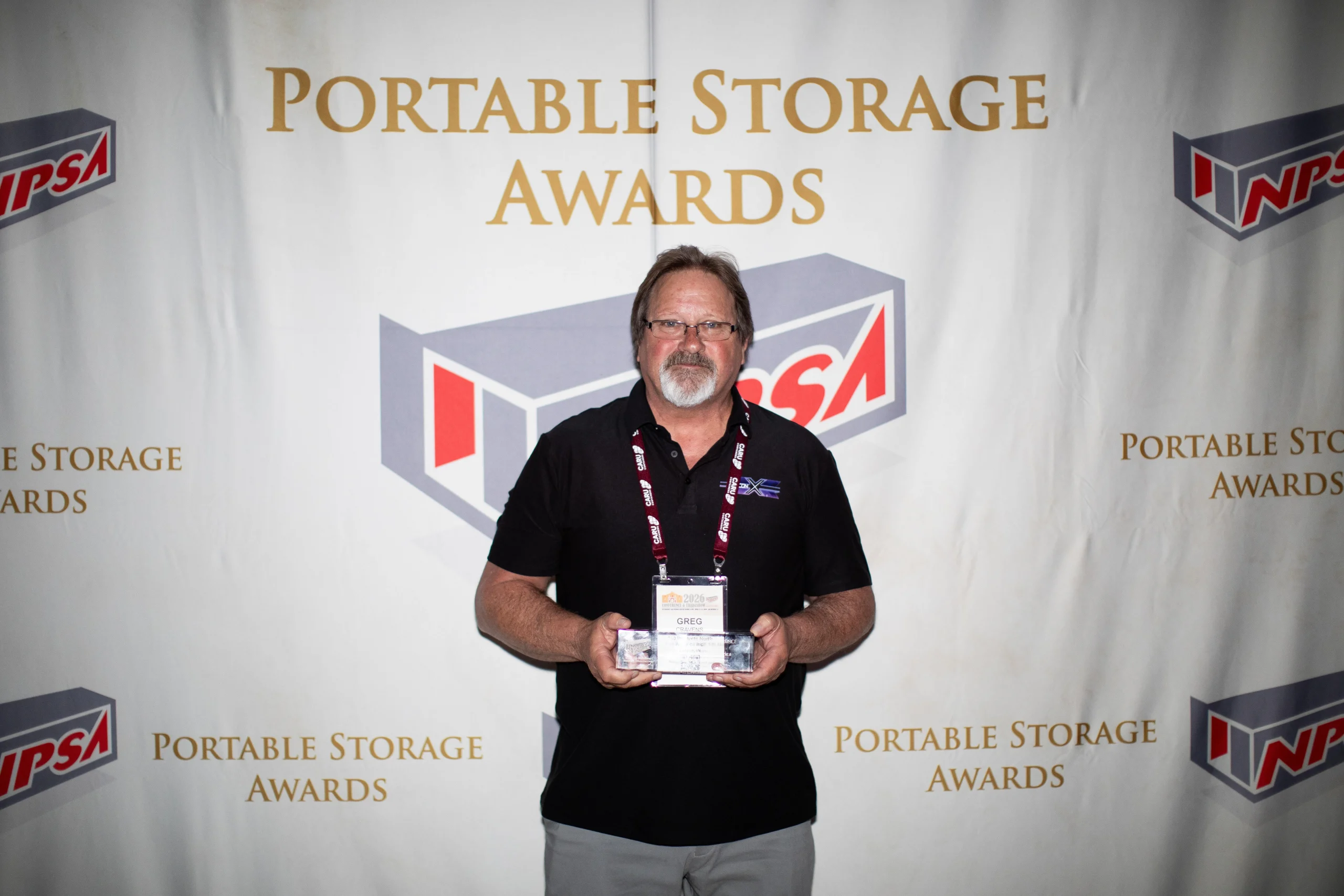Greg Cravens of 260 Products at the POrtable Storage Awards - holding the clear rectangular NPSA 2026 Innovative Award for their shipping container vent system, DRY-CON X®